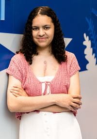 Dark-haired teen wearing white dress wtih pink knitted vest