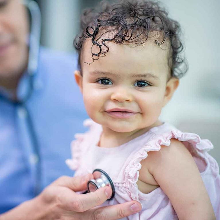 Close up of happy baby being examined with a stethoscope. 