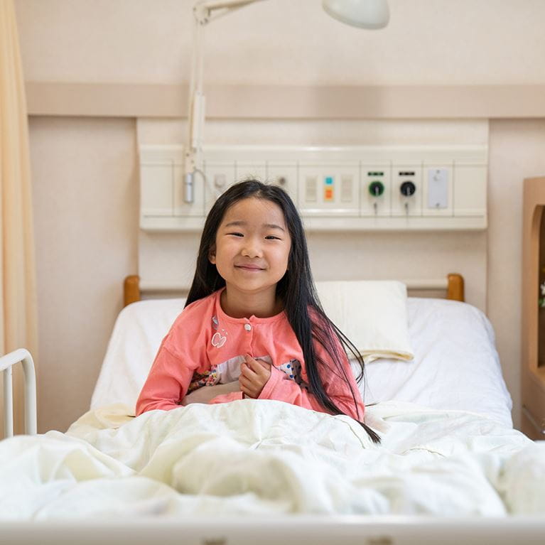 Happy girl sitting in hospital bed. 