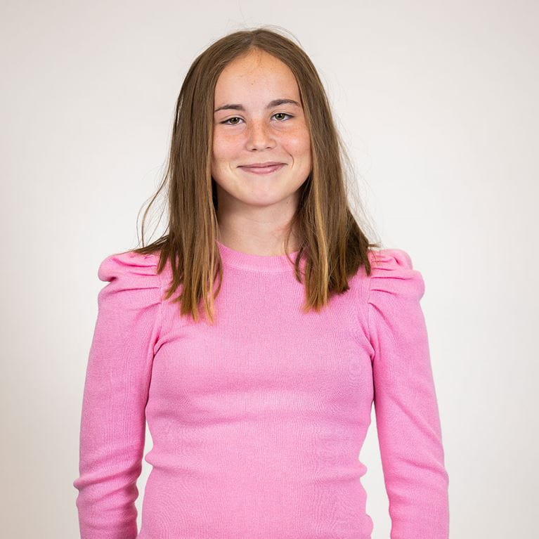Smiling teenage girl wearing pink shirt.
