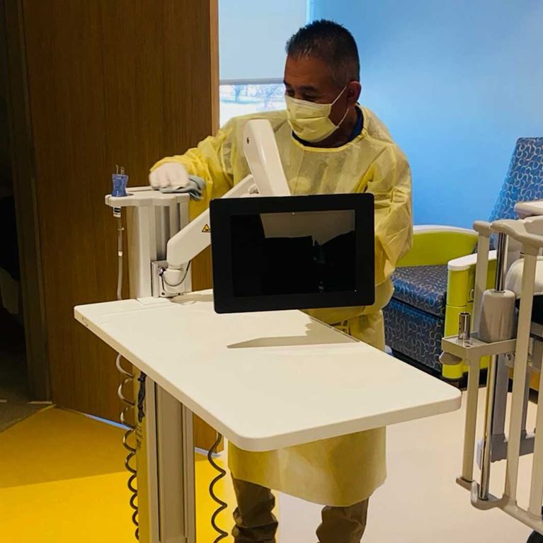 Masked, ACH team member cleaning a patient room.