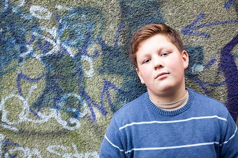 Teenage boy standing against a wall.