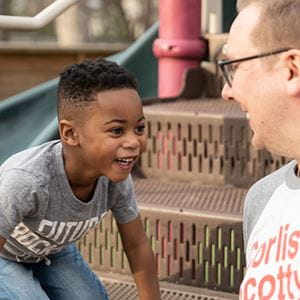 Happy, healthy boy playing with dad on playground.