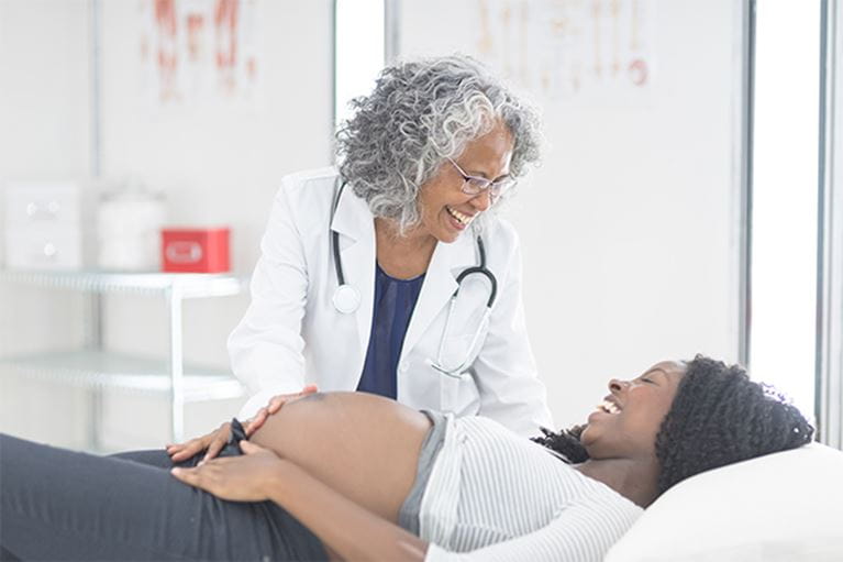 Doctor laughing with pregnant mother.