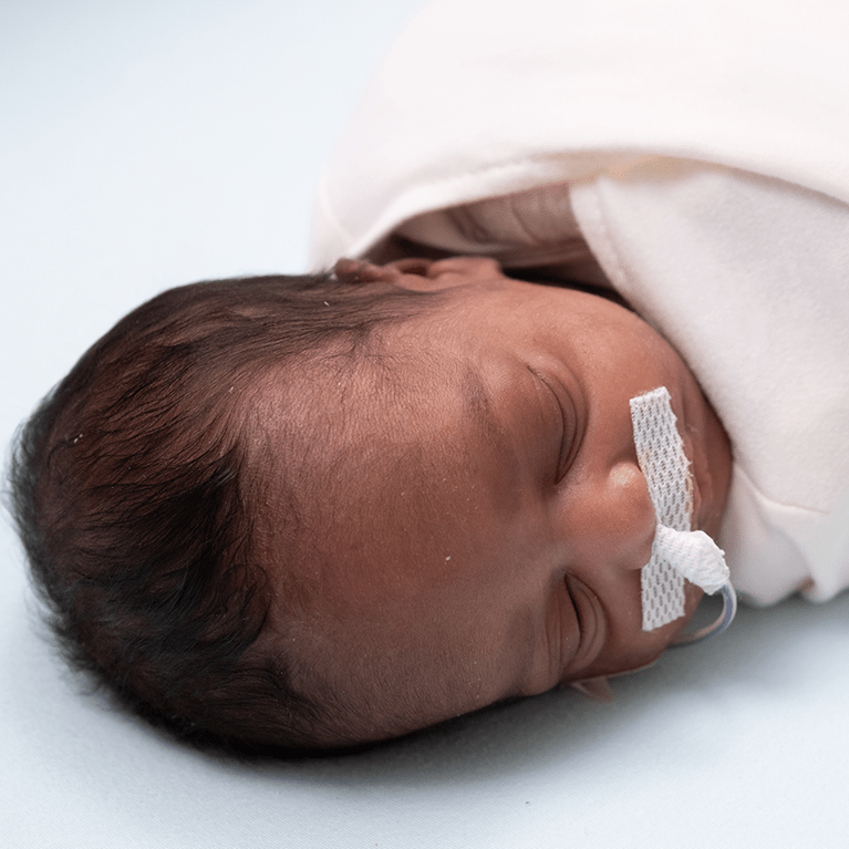 Infant wrapped in white blanket.